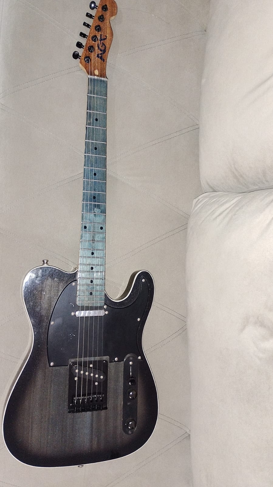 Vista frontal da guitarra AGT no sofá, com escudo preto, captadores e controles